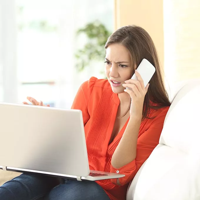 woman on phone looking at laptop