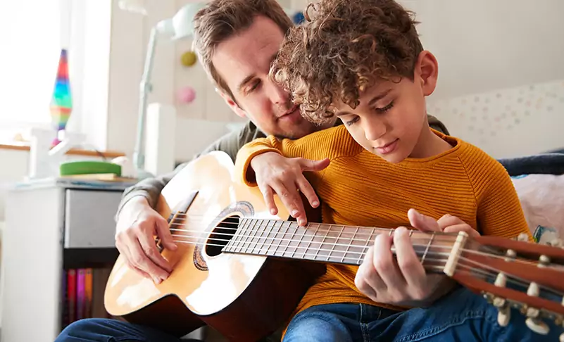 image of father and son playing guitar together