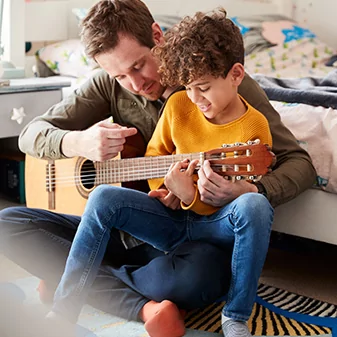 image of father and son playing guitar