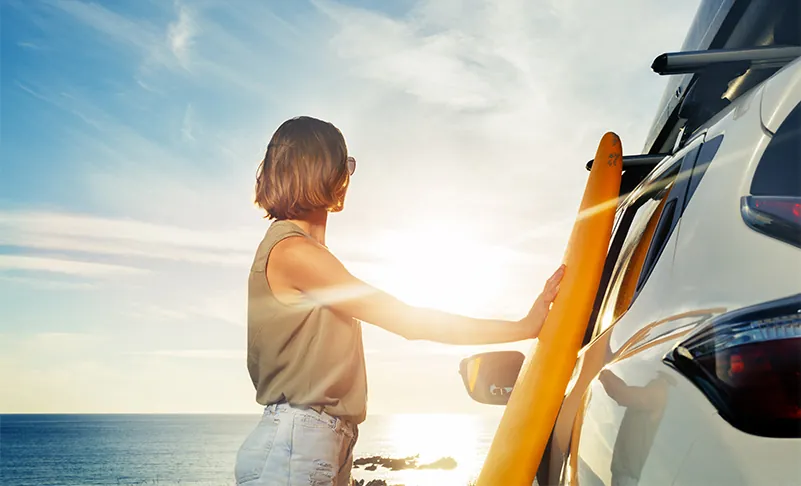 woman standing by her car by the beach