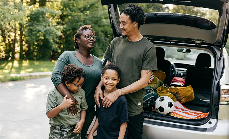 family smiling by car trunk