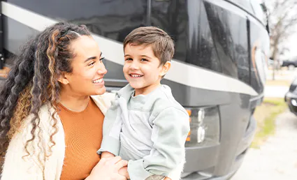 mother smiling next to RV with young boy