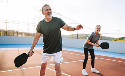 older couple playing pickleball outside