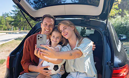 family taking selfie in car trunk