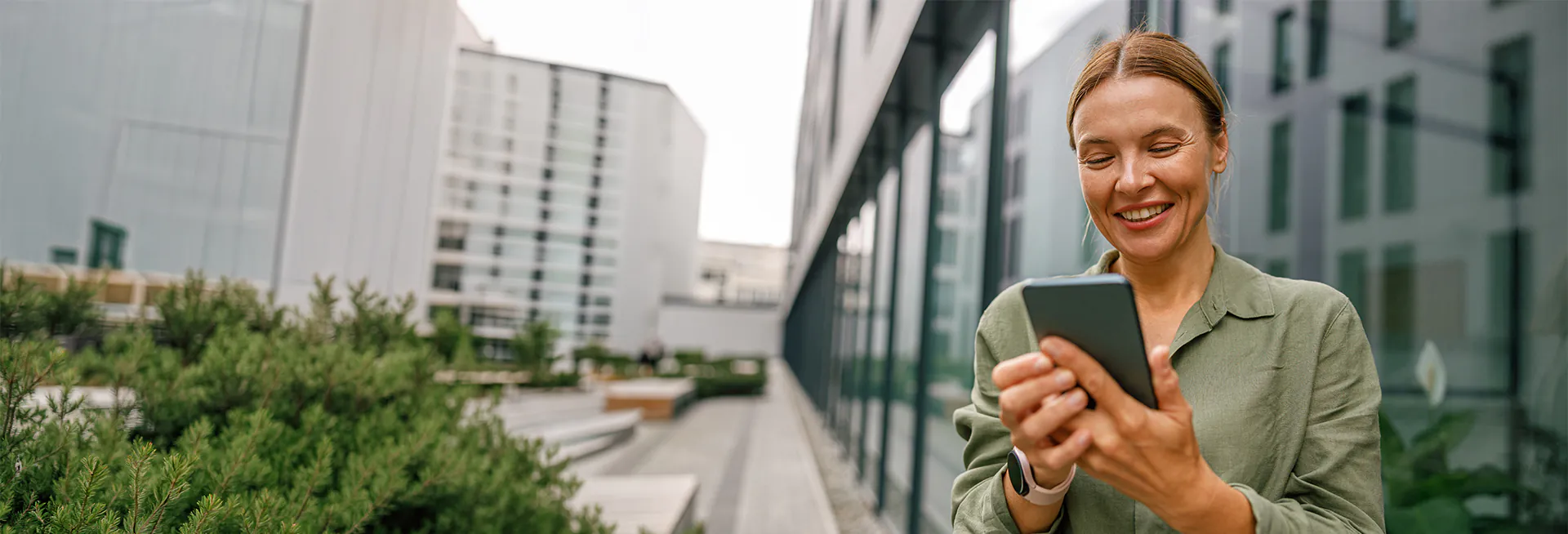 woman smiling while looking at phone outside